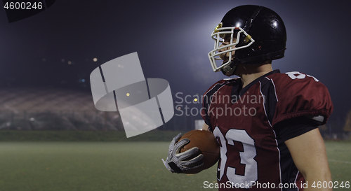 Image of American football player holding ball while running on field