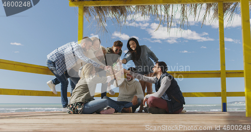 Image of Group of friends having fun on autumn day at beach