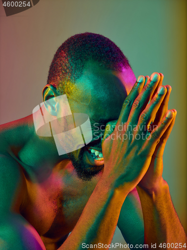 Image of Close up portrait of a young naked african man crying at camera indoors