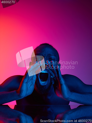 Image of Close up portrait of a young naked african man screaming at camera indoors