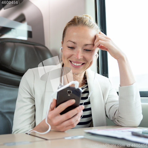 Image of Businesswoman communicating on mobile phone while traveling by train.