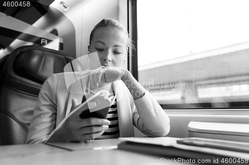 Image of Businesswoman communicating on mobile phone while traveling by train.