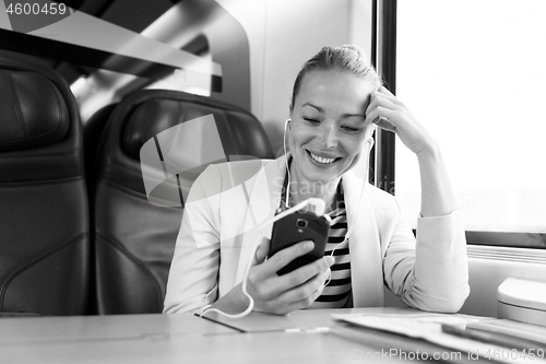 Image of Businesswoman communicating on mobile phone while traveling by train.