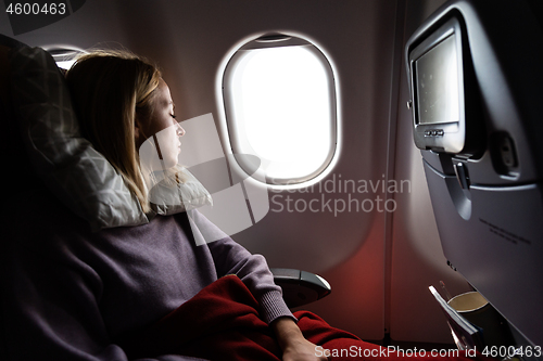 Image of Tired blonde casual caucasian lady sleepin on seat while traveling by airplane. Commercial transportation by planes.