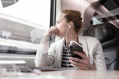 Image of Businesswoman communicating on mobile phone while traveling by train.