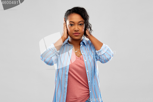 Image of african american woman closing ears by hands