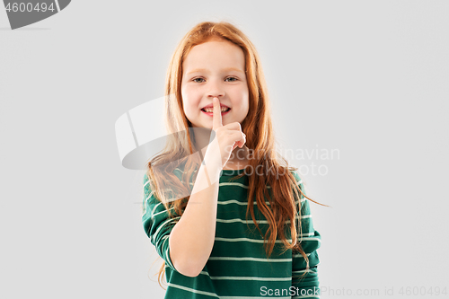 Image of smiling red haired girl making shush gesture