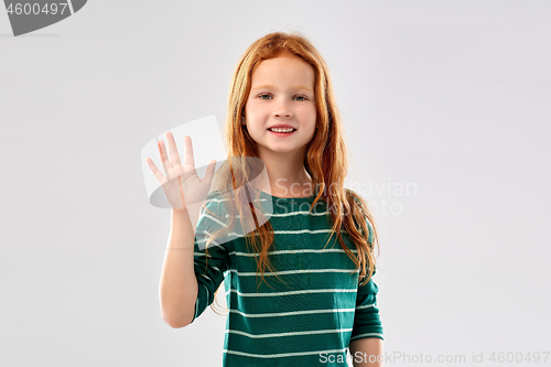 Image of smiling red haired girl waving hand