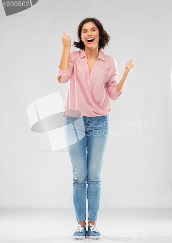 Image of young woman in shirt and jeans celebrating success