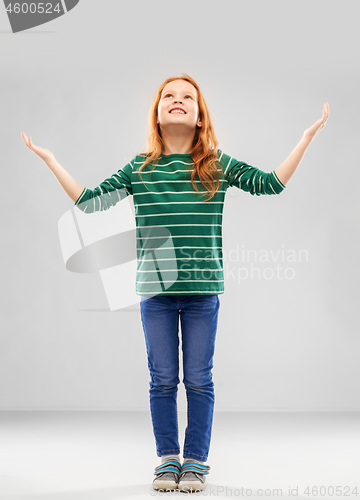 Image of happy grateful red haired girl looking up above