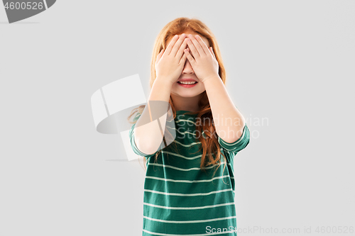 Image of smiling red haired girl with eyes closed by hands