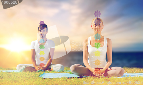 Image of couple doing yoga in lotus pose with seven chakras