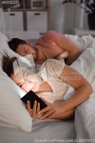 Image of woman using smartphone while boyfriend is sleeping