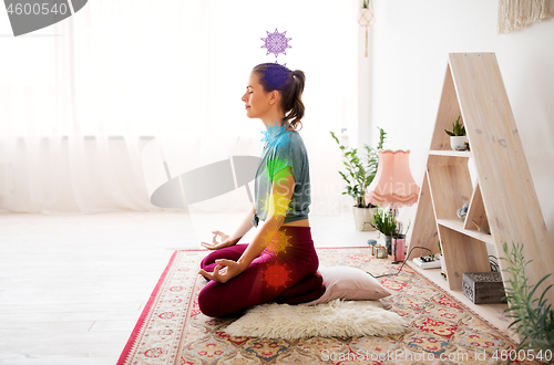 Image of woman meditating in lotus pose at yoga studio