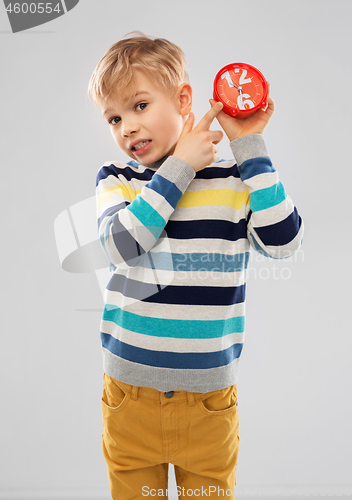 Image of nice boy in striped pullover with alarm clock