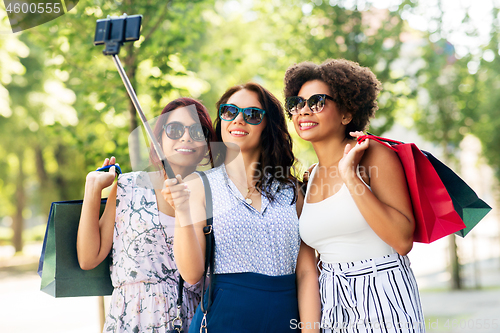 Image of women with shopping bags taking selfie outdoors