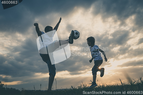 Image of Father and young little boy playing in the field  with soccer ba