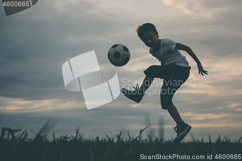 Image of Young little boy playing in the field  with soccer ball.