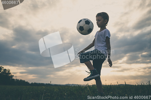 Image of Young little boy playing in the field  with soccer ball.