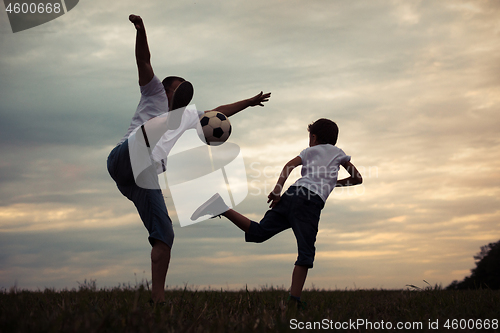 Image of Father and young little boy playing in the field  with soccer ba