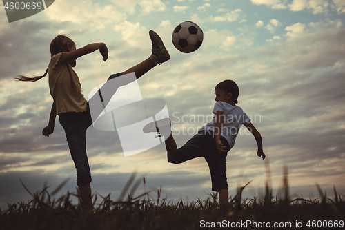 Image of Happy young little boy and girl playing in the field  with socce