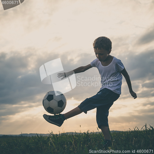 Image of Young little boy playing in the field  with soccer ball.