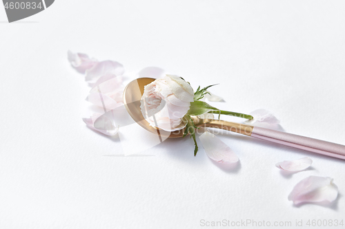 Image of Dessert spoon with roses and petals.