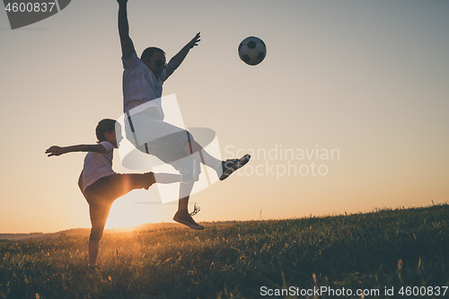 Image of Father and young little boy playing in the field  with soccer ba