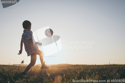 Image of Young little boy playing in the field  with soccer ball.