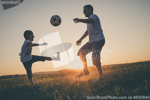 Image of Father and young little boy playing in the field  with soccer ba