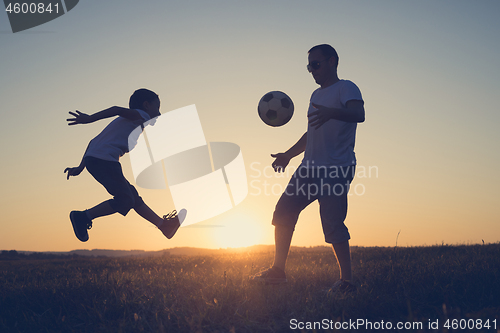 Image of Father and young little boy playing in the field  with soccer ba