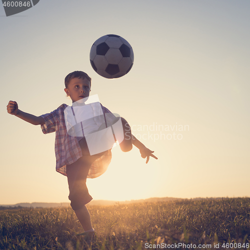 Image of Young little boy playing in the field  with soccer ball.