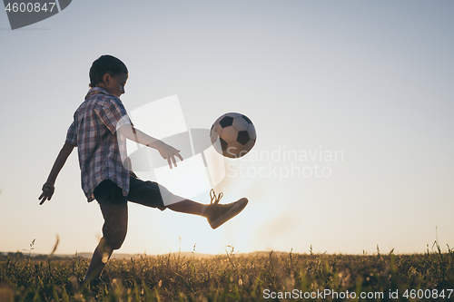 Image of Young little boy playing in the field  with soccer ball.