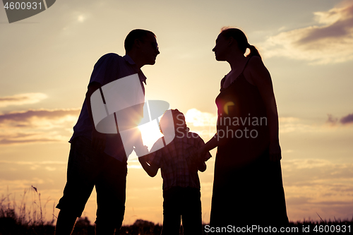 Image of Happy family standing in the park at the sunset time.