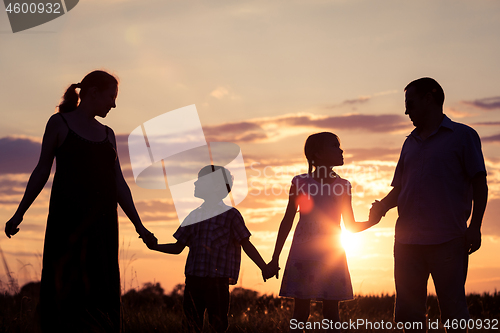 Image of Happy family standing on the field at the sunset time. They buil