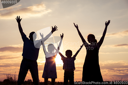Image of Happy family standing on the field at the sunset time. They buil