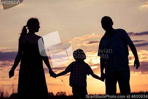 Image of Happy family standing in the park at the sunset time.