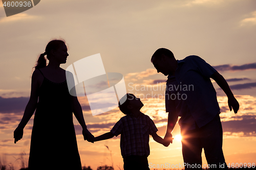 Image of Happy family standing in the park at the sunset time.