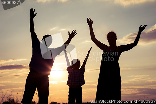 Image of Happy family standing in the park at the sunset time.