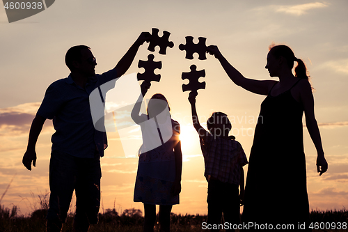 Image of Happy family standing in the park at the sunset time.