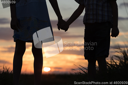 Image of Two children standing in the park at the sunset time.