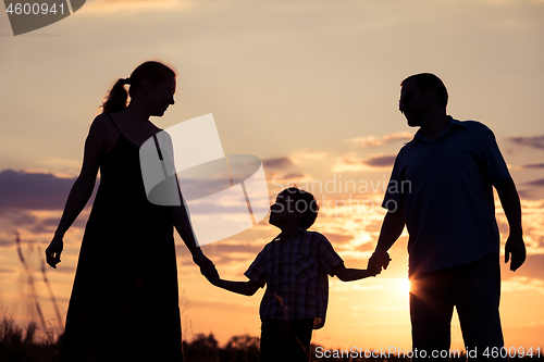 Image of Happy family standing in the park at the sunset time.