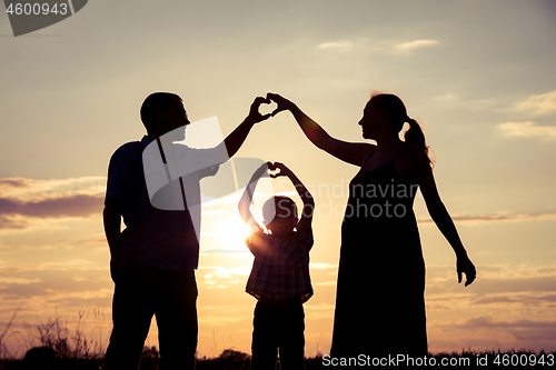 Image of Happy family standing in the park at the sunset time.