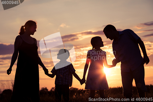 Image of Happy family standing in the park at the sunset time.