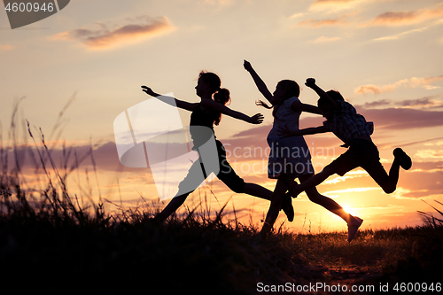 Image of Happy children playing in the park at the sunset time. 