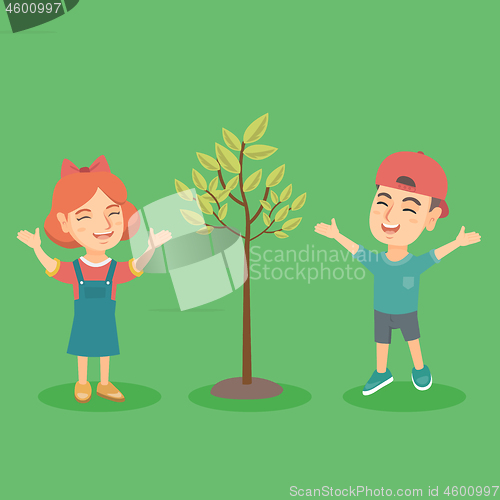 Image of Happy caucasian boy and girl jumping near the tree