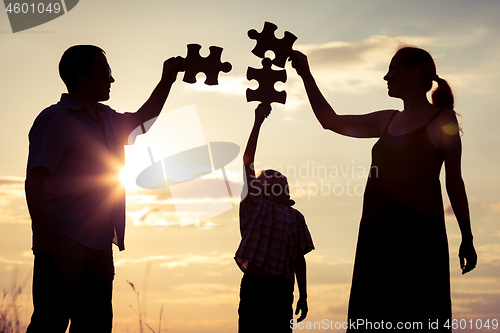 Image of Happy family standing in the park at the sunset time.