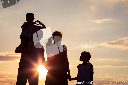 Image of Happy family standing in the park at the sunset time.