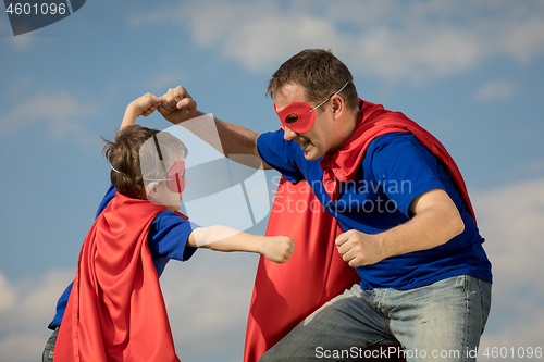 Image of Father and son playing superhero at the day time.