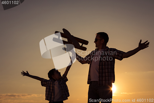 Image of Father and son playing with cardboard toy airplane 